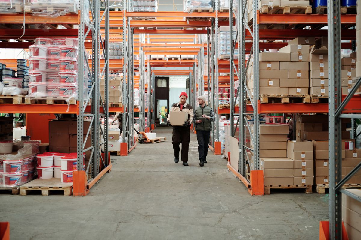 Two logistics professionals walking through a distribution warehouse aisle